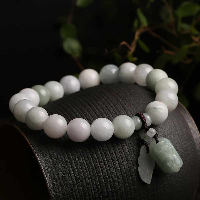 Natural Jade Pi Xiu Buddha Gourd Apple Success Bracelet – resting on curved wood with foliage background, nature
