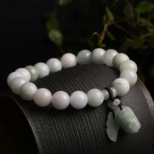 Natural Jade Pi Xiu Buddha Gourd Apple Success Bracelet – resting on curved wood with foliage background, nature