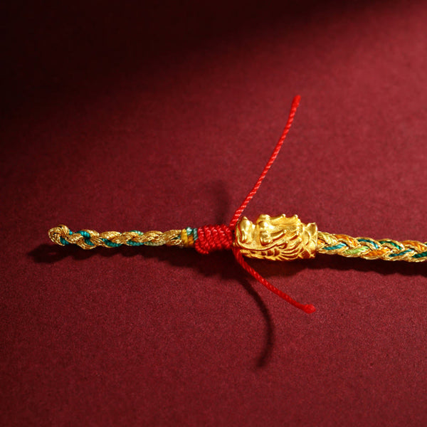 Year of the Dragon Braided Bracelet - Flat lay with gold dragon head and red tassel ends, Dragon motif