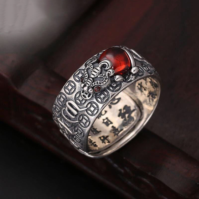 Feng Shui PiXiu Ring – Close-up of silver ring with red garnet on dark wood, wealth power jewelry