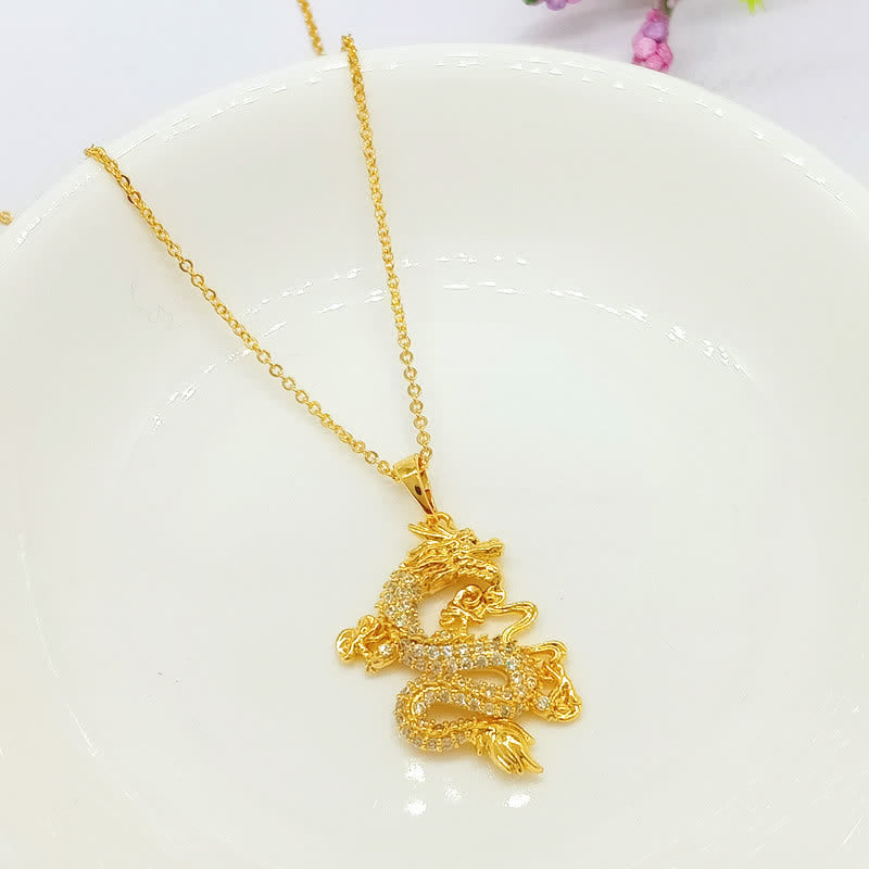 Gold Dragon Protection Necklace – Pavé crystal dragon pendant on gold chain, white ceramic dish, Elegance