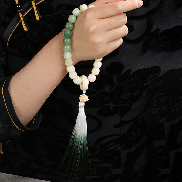 Bodhi Seed Lotus Wisdom Wrist Mala – Green gradient bracelet on wrist with black Tang suit, gold piping and lotus tassel, cultural jewelry