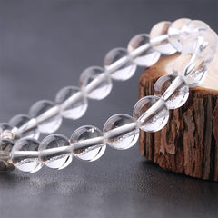 Tree of Life clear quartz bracelet with transparent round beads on elastic cord, displayed on wooden stand holder.