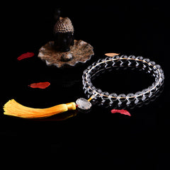 White Crystal Lotus Mala – faceted crystal prayer beads coiled near dark stone Buddha head, mindfulness