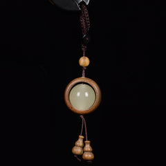 Feng Shui Sandalwood Keychain with Luminous Bead – Green sandalwood circular frame with glowing jade center and double gourd pendant on black background