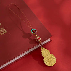 Antique gold gourd keychain with red enamel bead on red book, red background