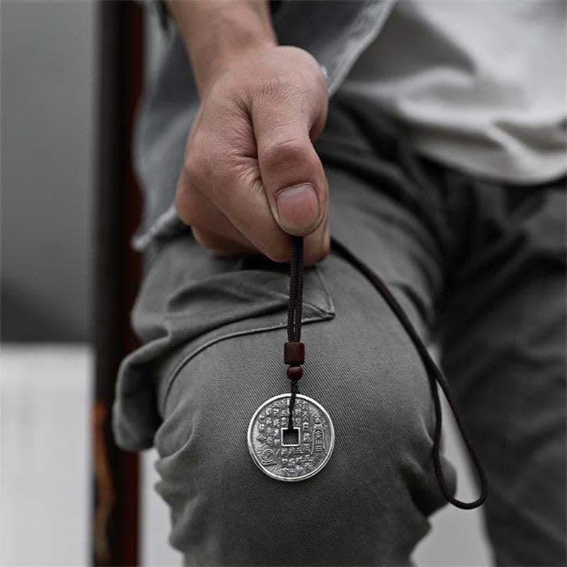 Bagua Yin Yang Obsidian Necklace - silver coin pendant with red bead held by hand, bokeh background