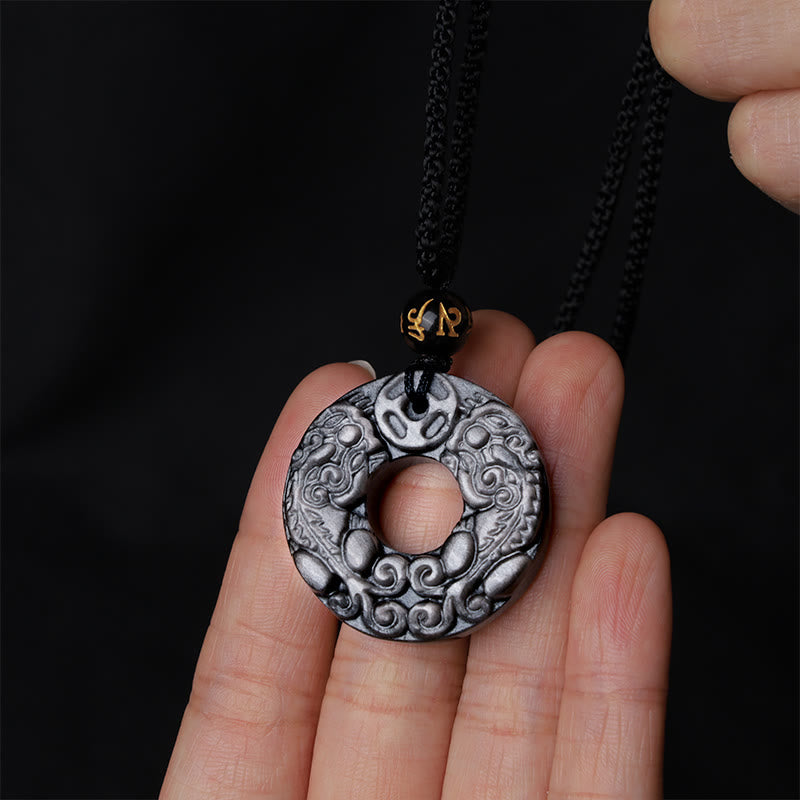 Silver Sheen Obsidian Double PiXiu Necklace – Hand holding obsidian PiXiu disc against black backdrop, amulet