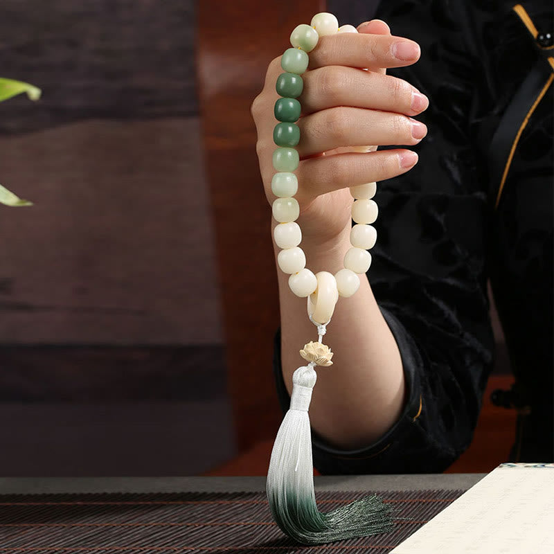Bodhi Seed Lotus Wisdom Wrist Mala – Handheld mala with lotus carving in dark traditional setting, bamboo mat and green foliage, zen practice