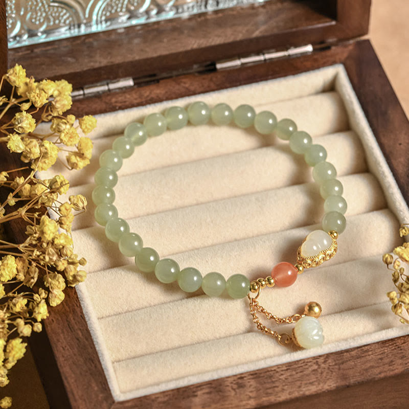 Hetian Jade Gourd Lotus Bracelet resting in antique wooden jewelry box with dried flowers, heritage luck gift