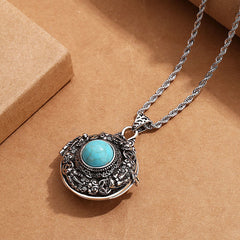 Tibetan Pi Xiu Necklace – Ornate silver locket with turquoise stone on brown paper