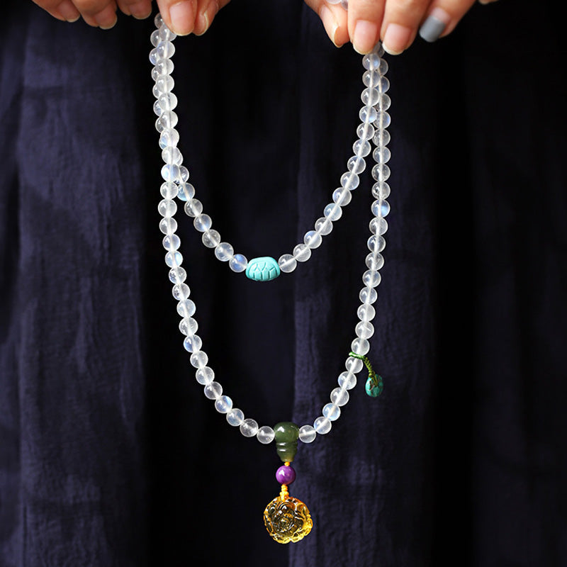 Moonstone Amber Turquoise Lotus Mala - Moonstone necklace with turquoise and gold pendant, held in hands