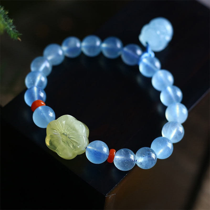 Aquamarine PiXiu Bracelet – Circular layout on black reflective surface, blue beads, yellow flower, red accents