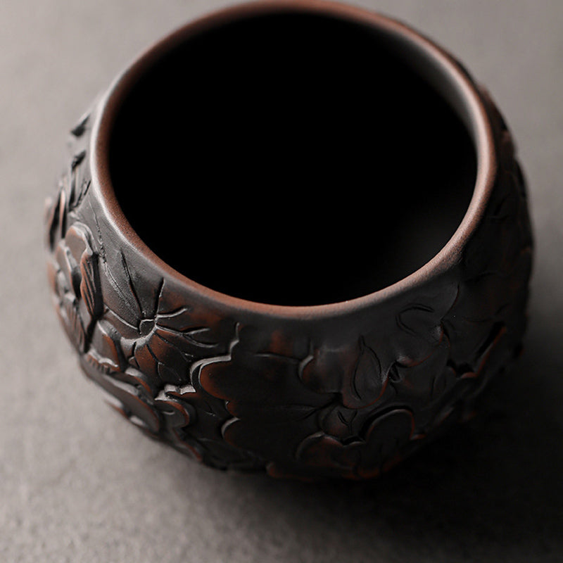 Ceramic Tea Cup – Lotus relief under dramatic studio lighting, dark backdrop, carved tea bowl