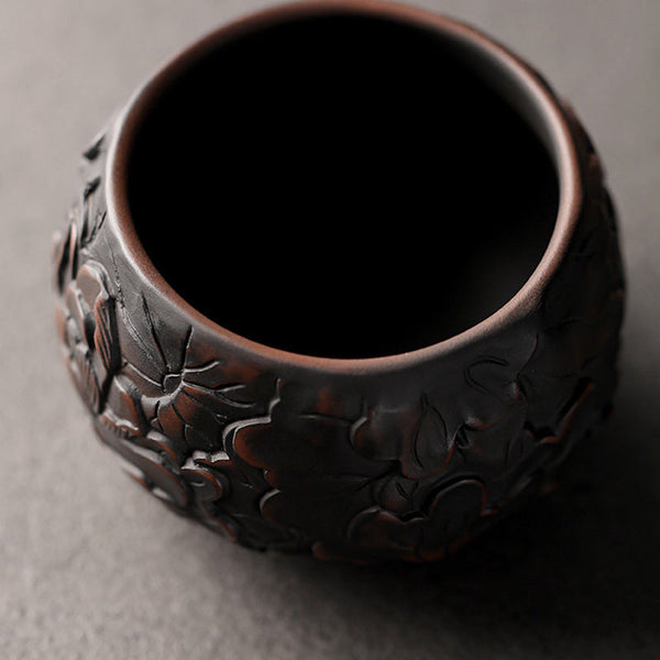 Ceramic Tea Cup – Lotus relief under dramatic studio lighting, dark backdrop, carved tea bowl