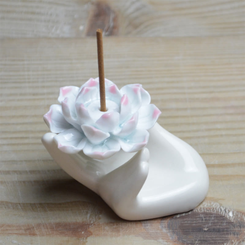 Ceramic Lotus Hand Incense Burner - cupped palm with pink-edged lotus on warm wood, healing