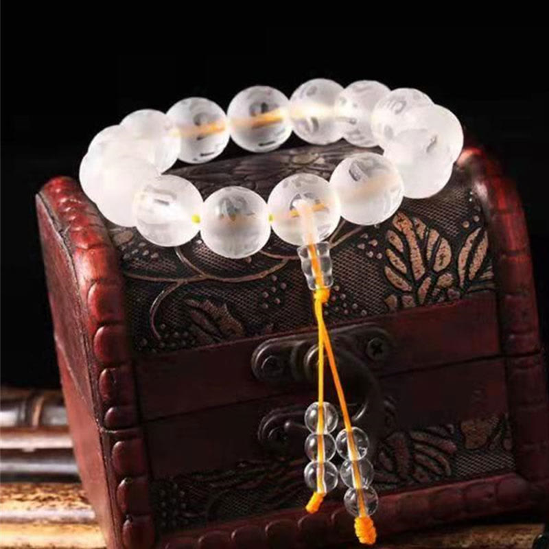 White Crystal Om Mani Padme Hum Bracelet – resting on ornate wooden box, tassel detail