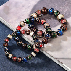 Colorful Liuli Glass Bead Luck Bracelet – Vibrant multicolored glass beads with pale blue center bead and gold spring-ring clasp on cream silk fabric, low angle