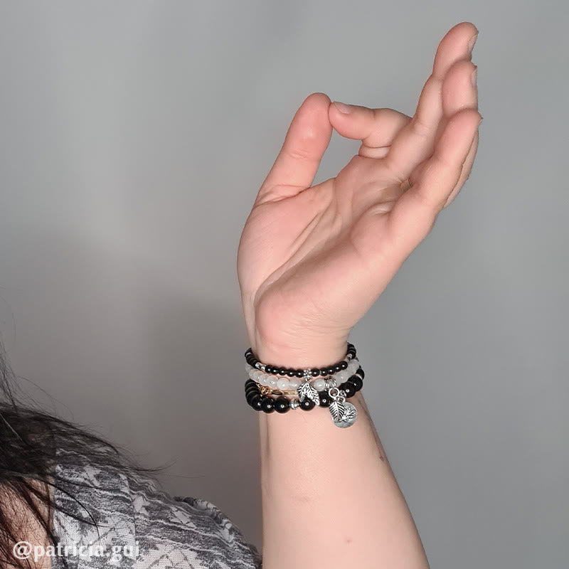 Lotus Bracelet Set – black and white beaded stretch bracelets with silver angel wing charm on wrist, boho bracelet