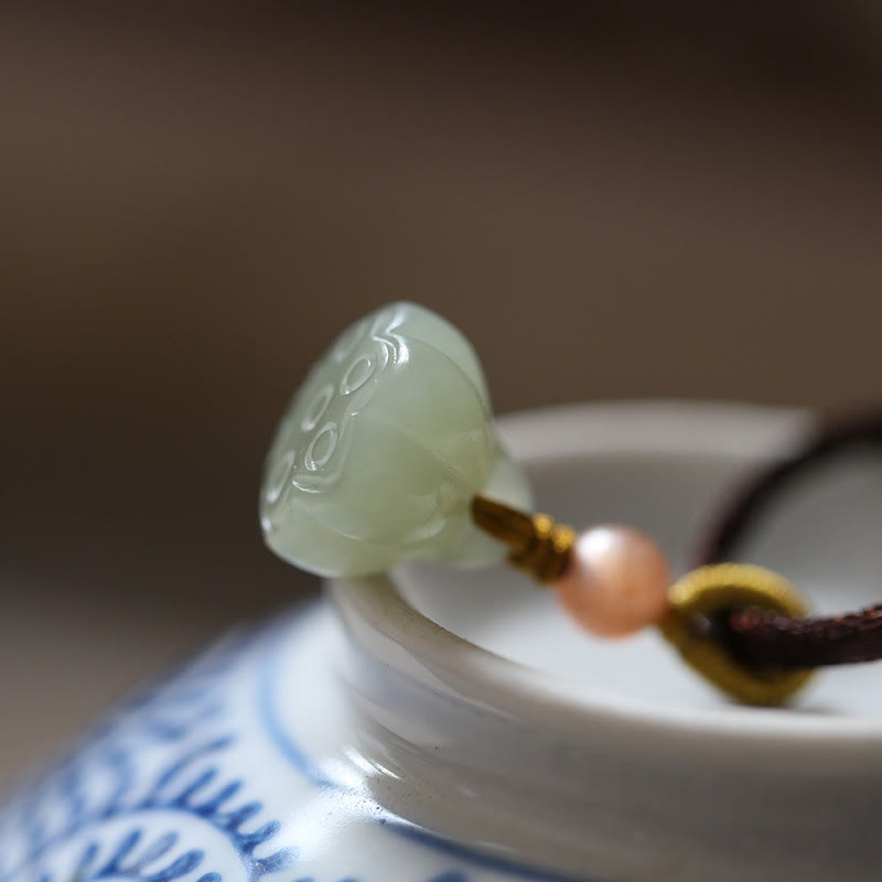 Jade Peace Buckle Lotus Necklace – Lotus seed pod jade pendant on brown cord on blue-and-white porcelain, lotus jade