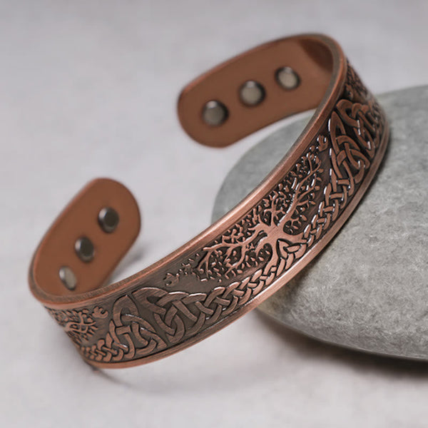 Solid copper cuff bracelet featuring hand-engraved tree of life with Celtic triquetra knots and six magnetic inlays at terminals on gray river stone