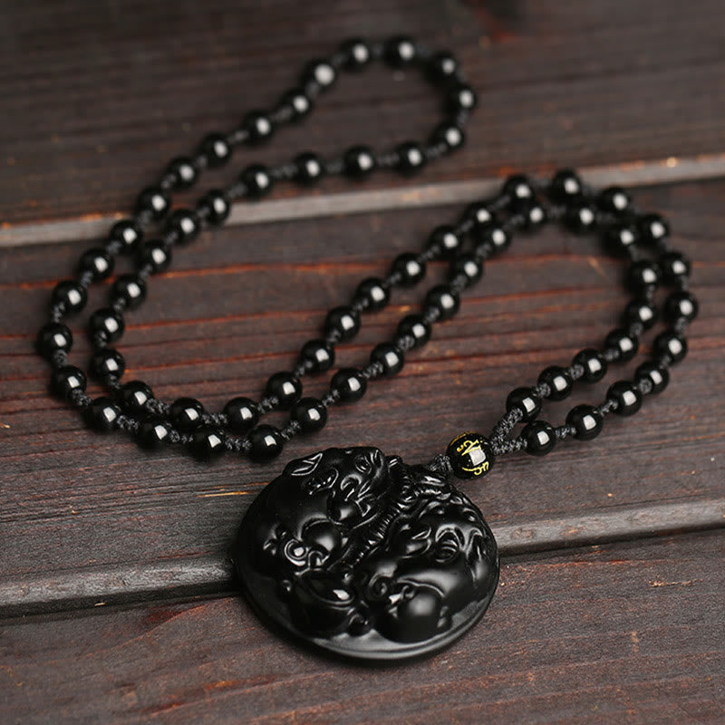 Double PiXiu Necklace – Black obsidian PiXiu disc with beaded rope chain on dark wood surface, protection necklace