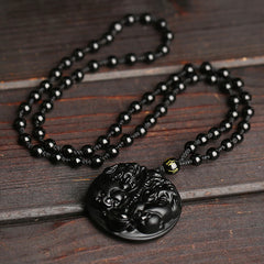 Double PiXiu Necklace – Black obsidian PiXiu disc with beaded rope chain on dark wood surface, protection necklace