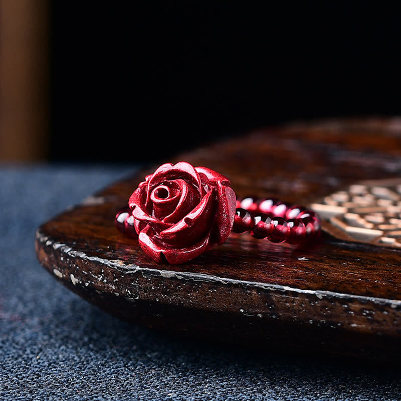 Garnet Cinnabar Ring – cinnabar carved rose ring dark wood tray, artistic protection detail