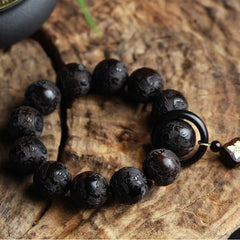 Ebony Wood Yin Yang Gourd Balance Bracelet - close-up of carved wooden beads on dark surface with ceramic vessel, ebony meditation jewelry