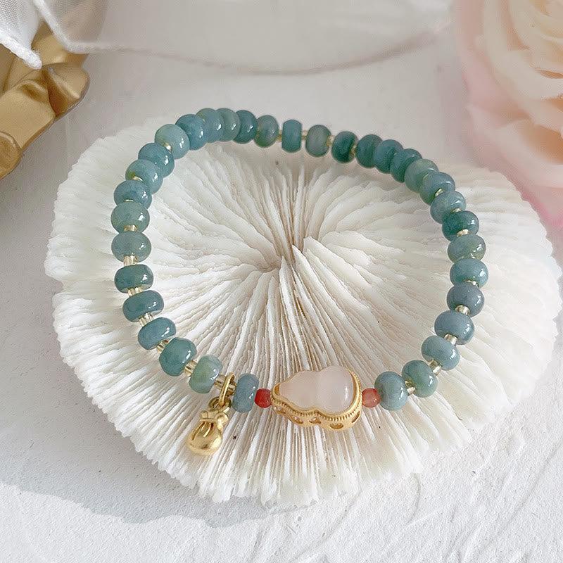 Hetian Jade Pearl Fu Gourd Money Bag Bracelet – Jade gourd bracelet with gold money bag charm on glass, wealth jewelry