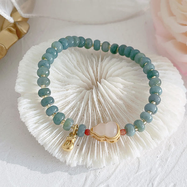 Hetian Jade Pearl Fu Gourd Money Bag Bracelet – Jade gourd bracelet with gold money bag charm on glass, wealth jewelry