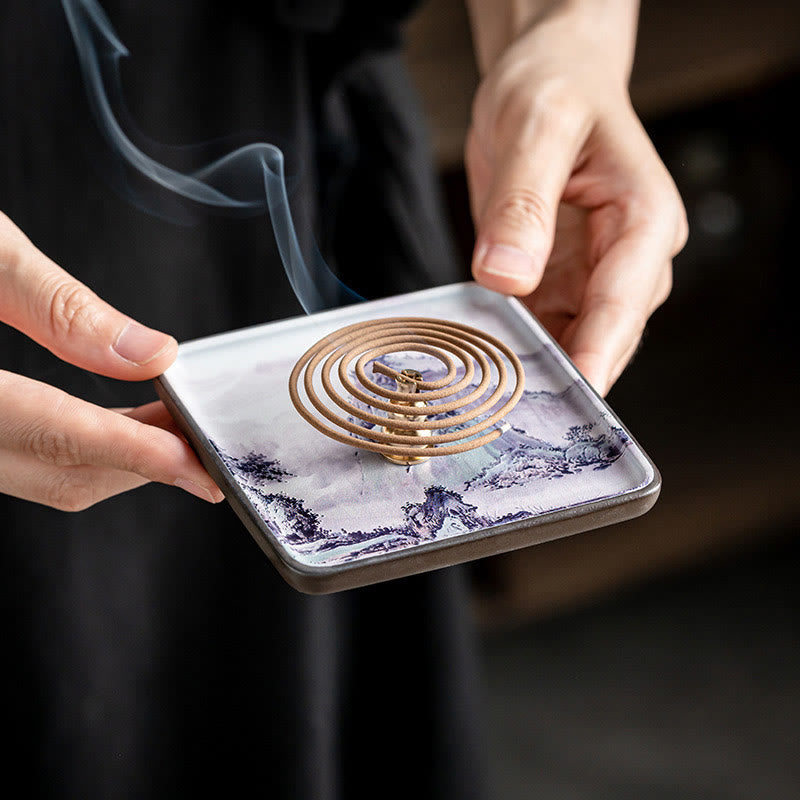 Blue Landscape Incense Plate – Coil incense burning on blue-and-white mountain ceramic dish, held by hands