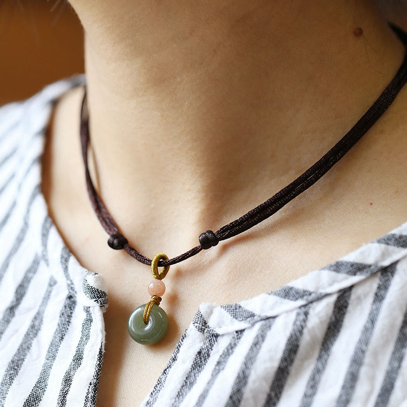 Jade Peace Buckle Lotus Necklace – Bi-disc jade pendant on brown cord with pink bead worn on neck, jade choker