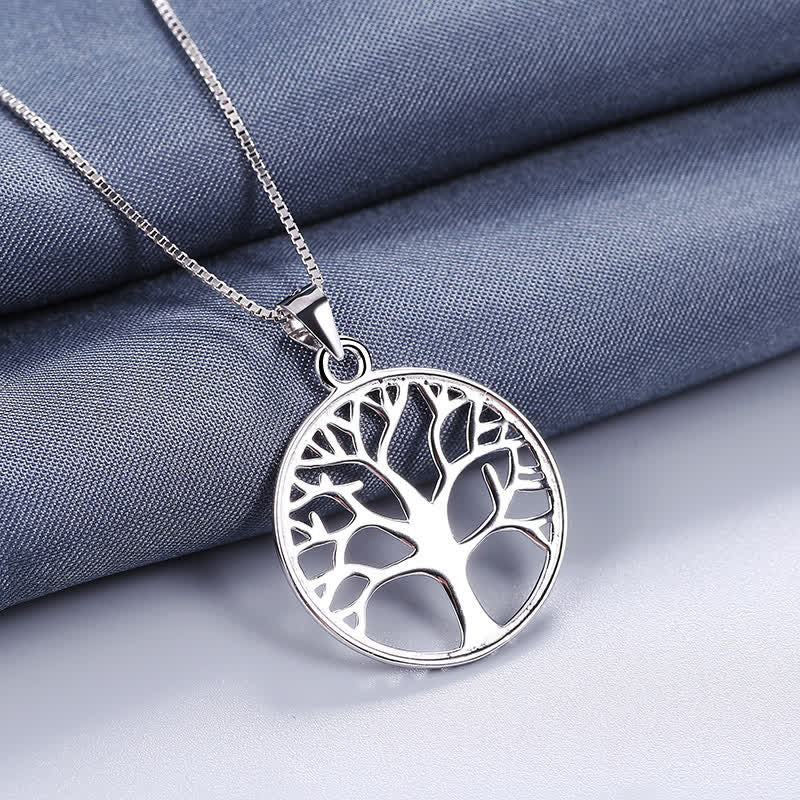 Tree of Life Sterling Silver Necklace – pendant on folded slate blue fabric with diagonal drape, polished sterling silver