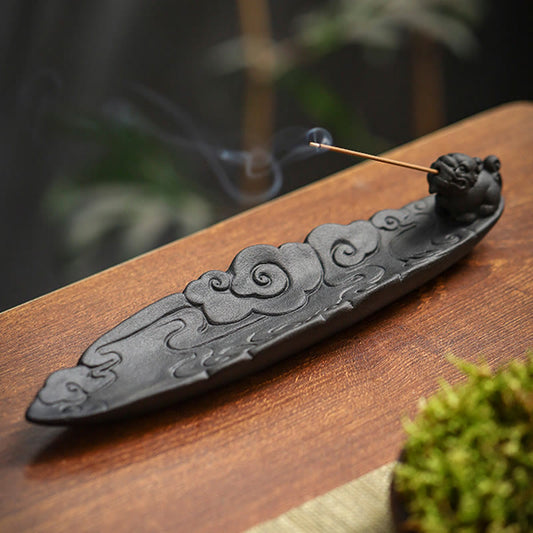 Cloud-pattern Pixiu incense holder with smoke curling on warm wood table, moss accent, garden bokeh – ceramic incense burner