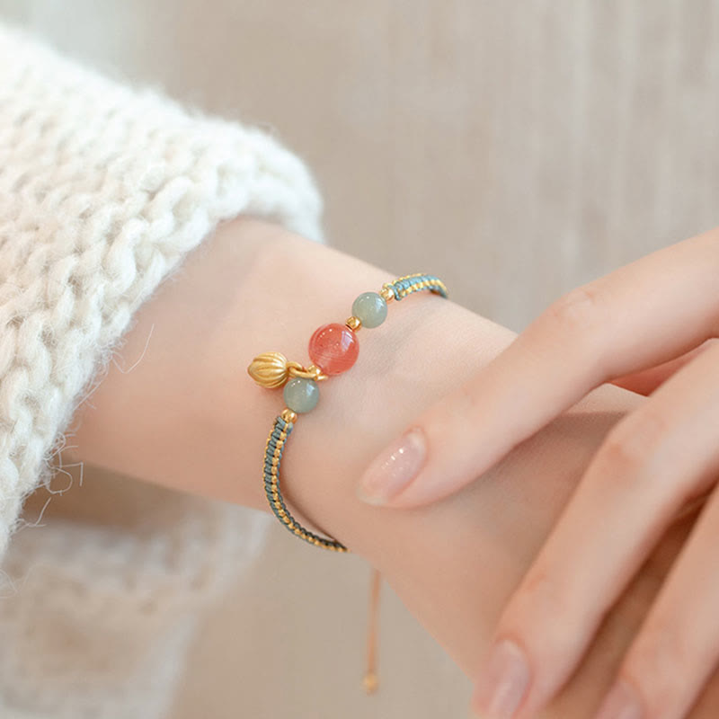 Red Agate Jade Lotus Bracelet – teal gold cord with coral pink and sage green beads, lotus pod charm, knit sleeve lifestyle shot