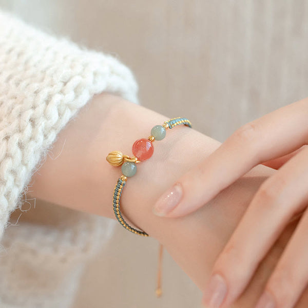 Red Agate Jade Lotus Bracelet – teal gold cord with coral pink and sage green beads, lotus pod charm, knit sleeve lifestyle shot