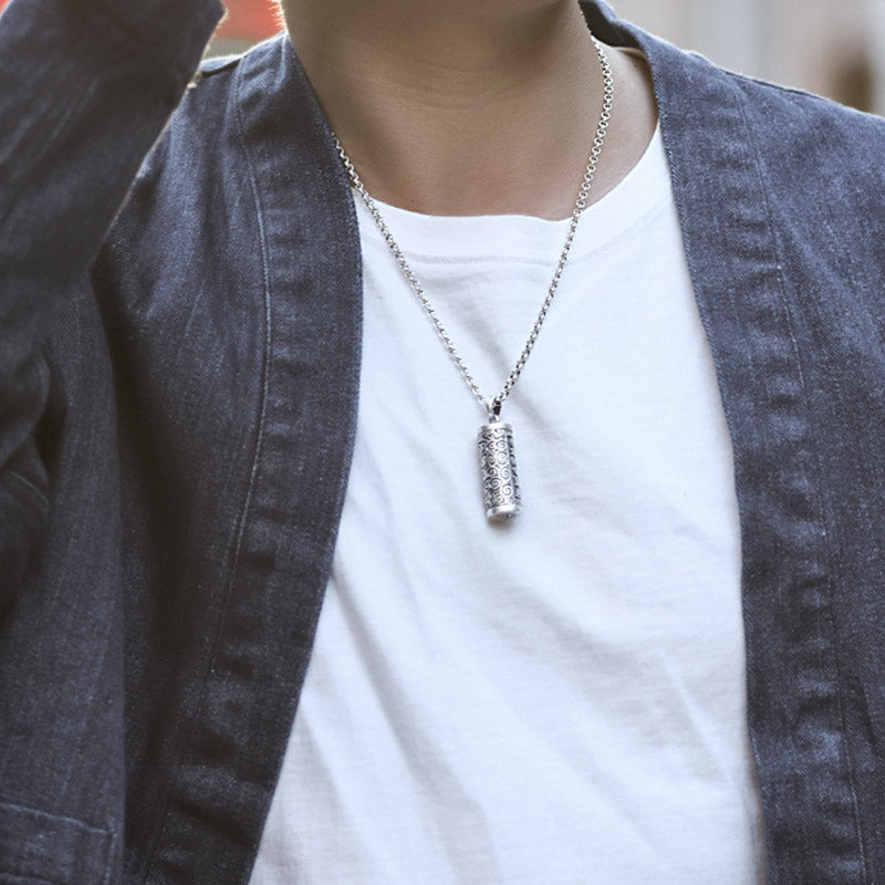 Om Mani Padme Hum Silver Protection Necklace – Silver ball chain necklace with cylindrical prayer wheel pendant worn on model in white t-shirt and dark denim jacket