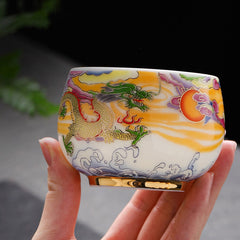 Dragon Phoenix Ceramic Teacup - Golden dragon cup cradled in hand with natural foliage, authentic