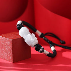 Natural Jade PiXiu Bracelet – side angle on red block, carved white jade detail, black cord, jade bracelet luck