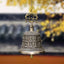 Tibetan Buddha Dragon Wind Chime Bell hanging from chain, warm bokeh background, tranquil, spiritual