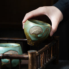 Lotus Pod Ceramic Kung Fu Tea Cup - Celadon cup held in hand showing ginkgo detail, mindfulness craft