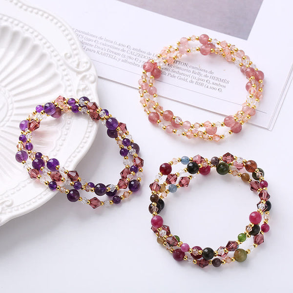 Three boho gemstone bracelets - amethyst purple, strawberry quartz pink, and multi-color tourmaline styles with crystal bicone beads and gold spacers, styled on white surface