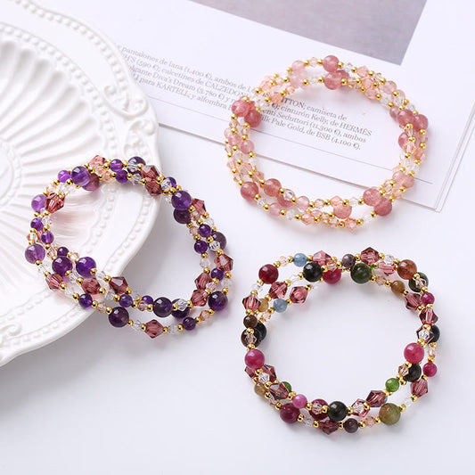 Three boho gemstone bracelets - amethyst purple, strawberry quartz pink, and multi-color tourmaline styles with crystal bicone beads and gold spacers, styled on white surface
