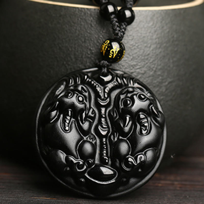 Double PiXiu Necklace – Black obsidian carved double PiXiu pendant against black ceramic cup, purification jewelry