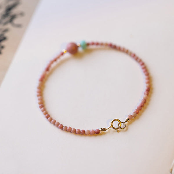 Rhodonite Loving Energy Bracelet – Pink-to-cream ombré stone beads with gold spring ring clasp and spacers on white background, soft bokeh
