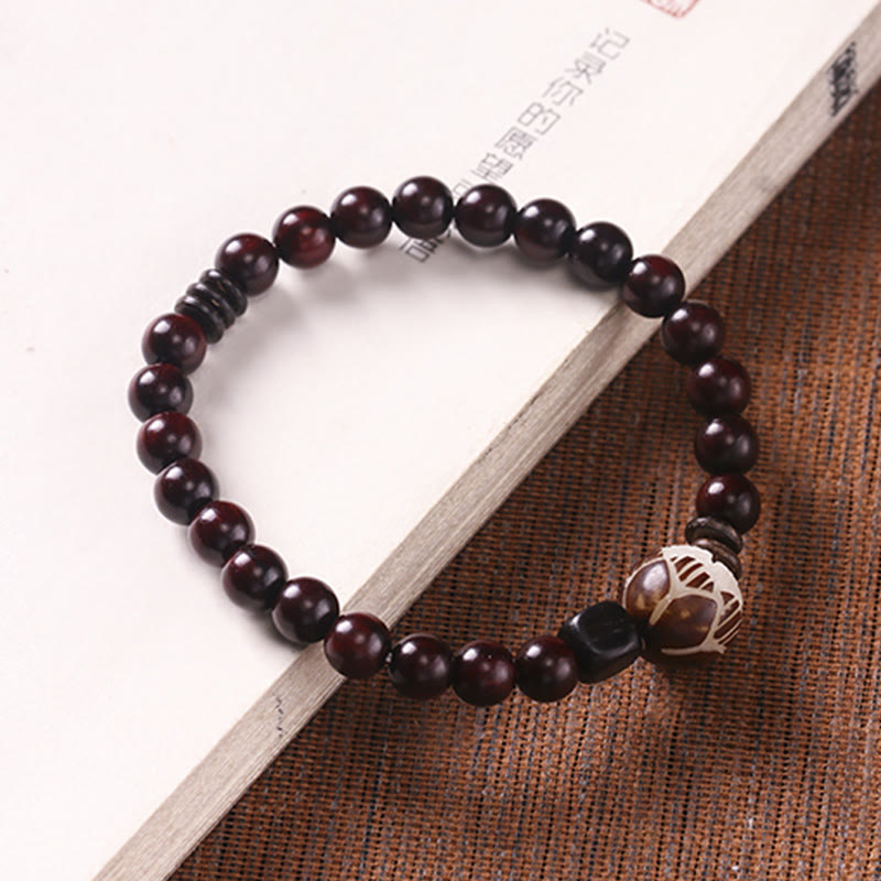 Red Sandalwood Lotus Bodhi Seed Bracelet – Red sandalwood beads with carved focal bead on woven mat, cultural styling