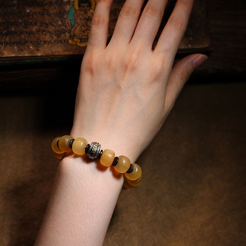 Tibetan Sheep Horn Skull Bracelet – Hand holding bracelet showing bead translucency and cord construction