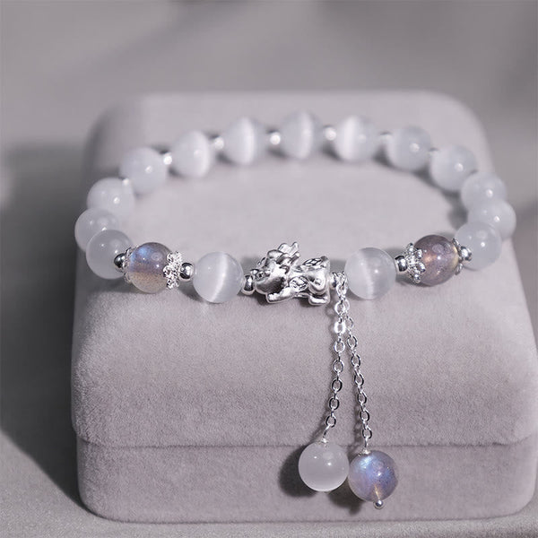 Cat's Eye PiXiu Bracelet – Close-up of silver PiXiu with chain tassels on plush gray jewelry box