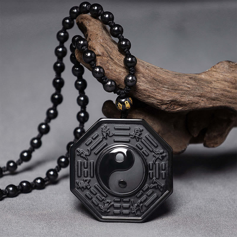 Black Obsidian Yin Yang Pendant Necklace - octagonal bagua pendant on black bead chain draped over driftwood, obsidian necklace